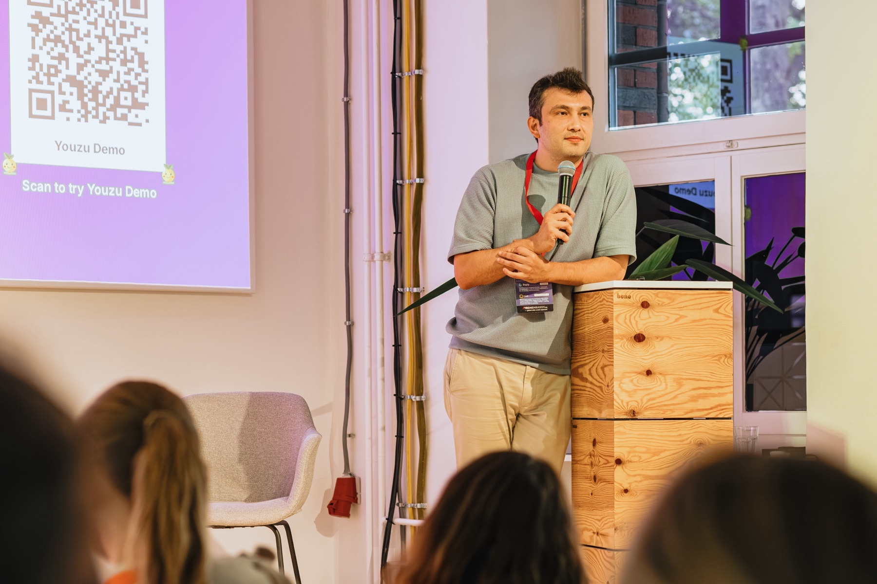 A speaker addressing guests from a wooden lectern at a TechEmbassy event.